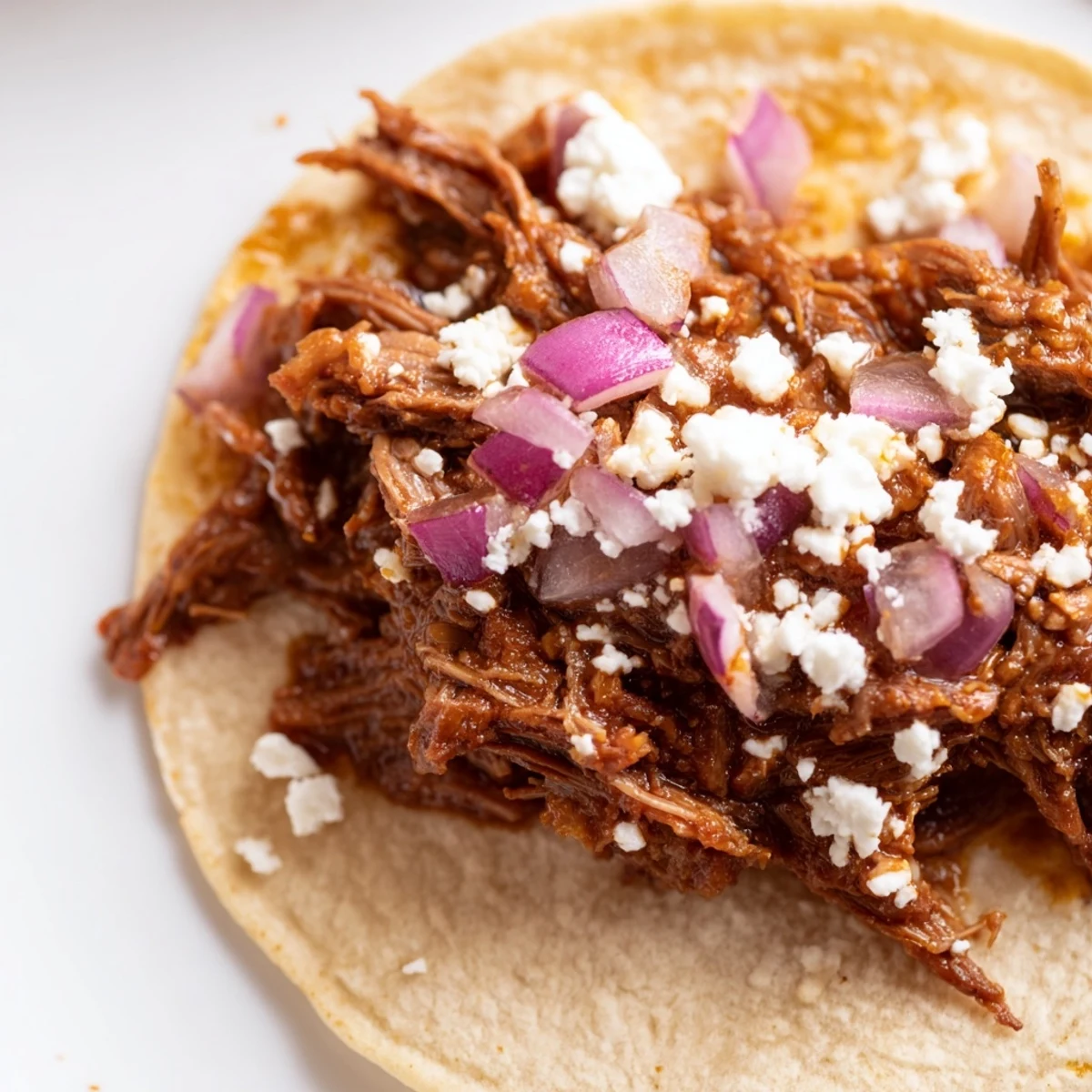 Close-up of slow cooker beef barbacoa tacos served with salsa and fresh lime wedges.