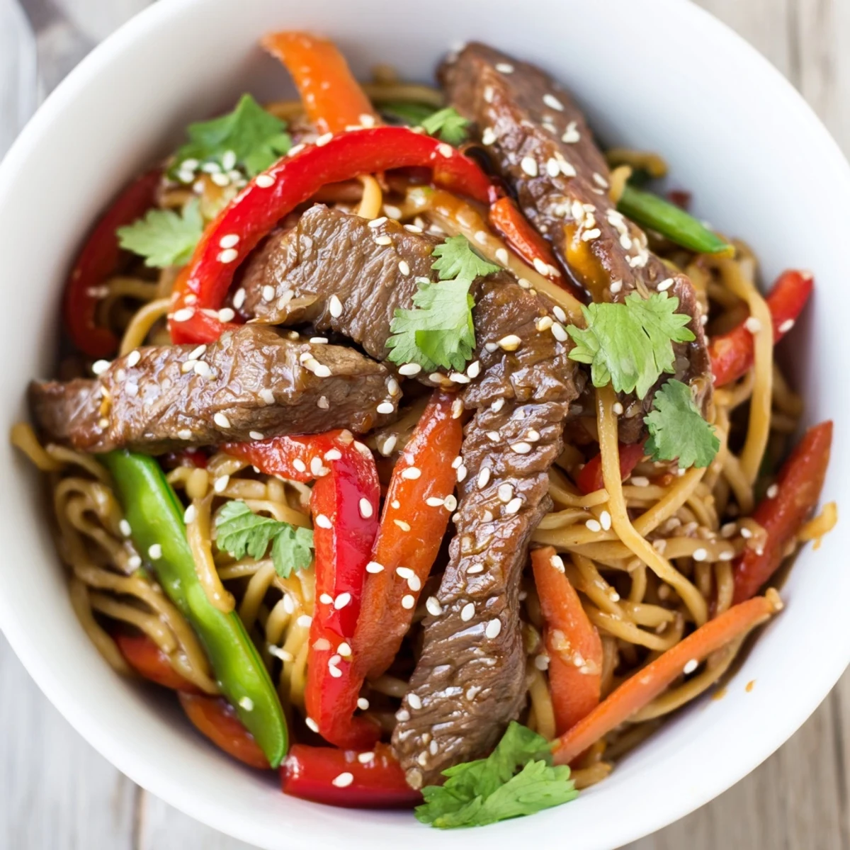 Easy Asian fusion Spicy Beef Noodles served with snap peas and carrots for a quick weeknight meal.