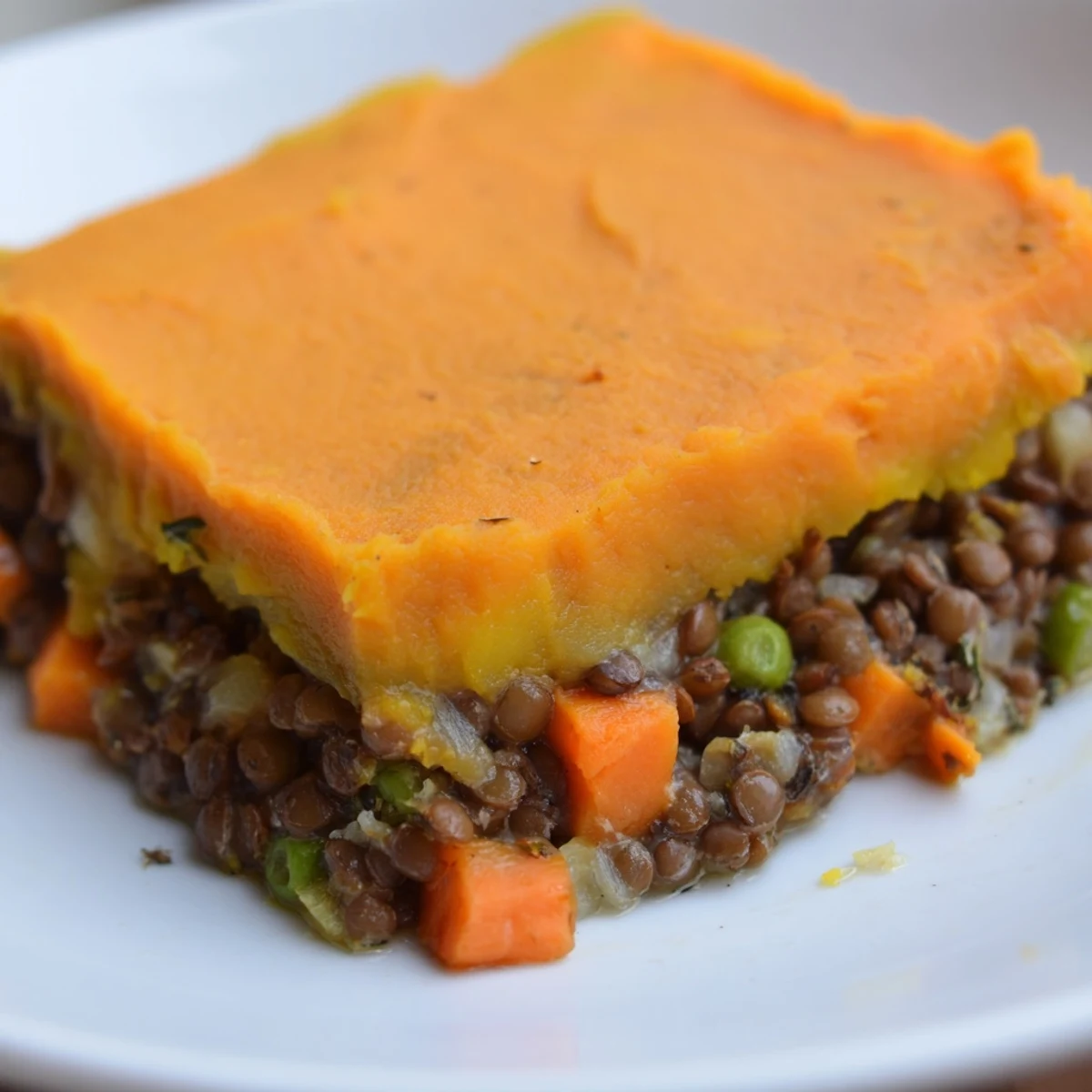 Golden brown Vegetarian Lentil Shepherds Pie with Sweet Potato mash bubbling in a ceramic dish.