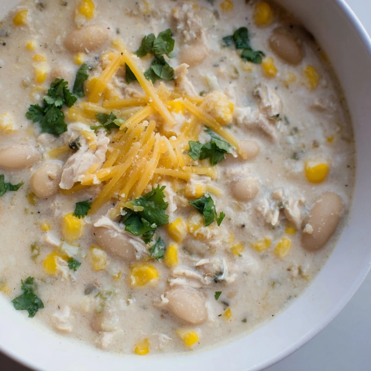 A hearty bowl of Creamy White Chicken Chili with Corn beside warm cornbread and a sprinkle of green onions.