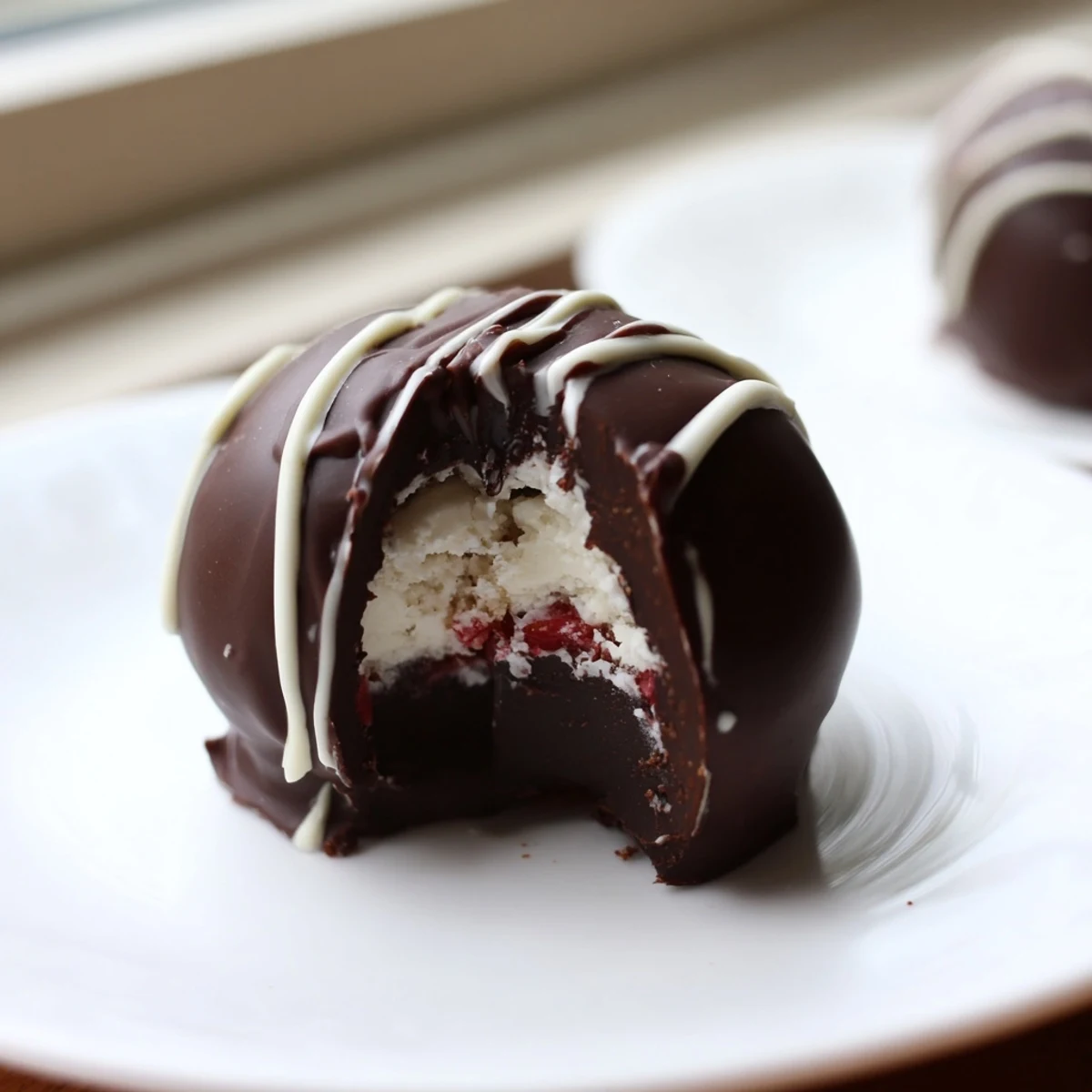 Close-up of glossy chocolate coated truffles garnished with strawberry powder for Chocolate Covered Strawberry Cheesecake Truffles.