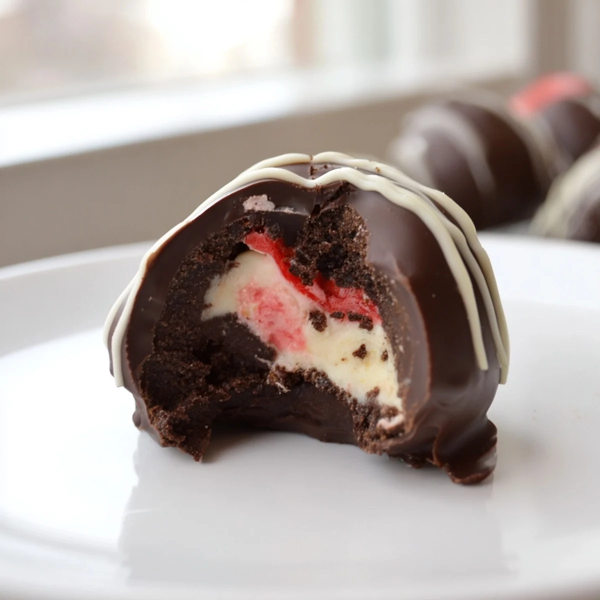 Velvety chocolate dipped cheesecake truffles rolled in graham crumbs and drizzled with white chocolate for a decadent finish.