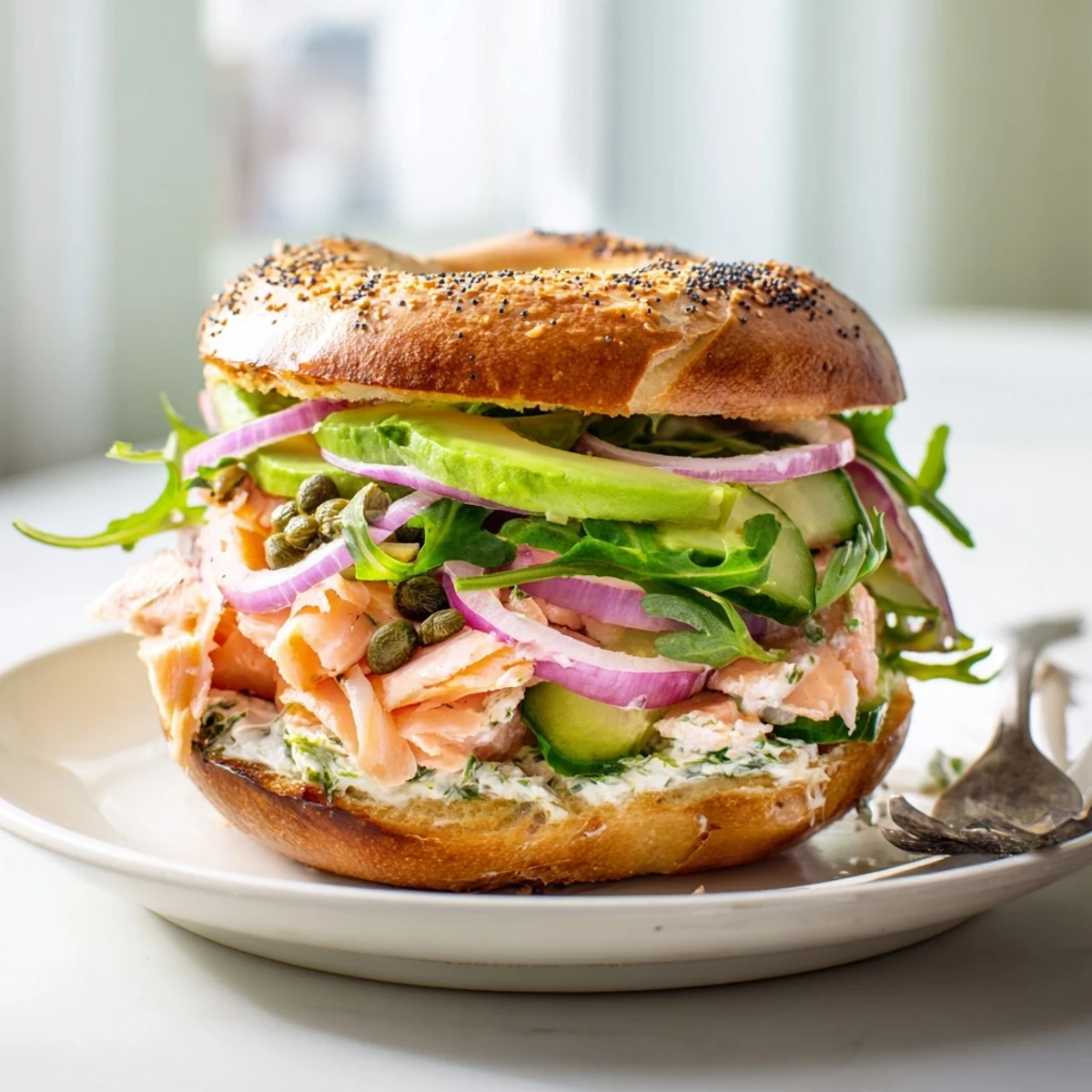 A close-up of a baked salmon brunch bagel with creamy spread, lemon zest, and fresh dill, ready to enjoy.