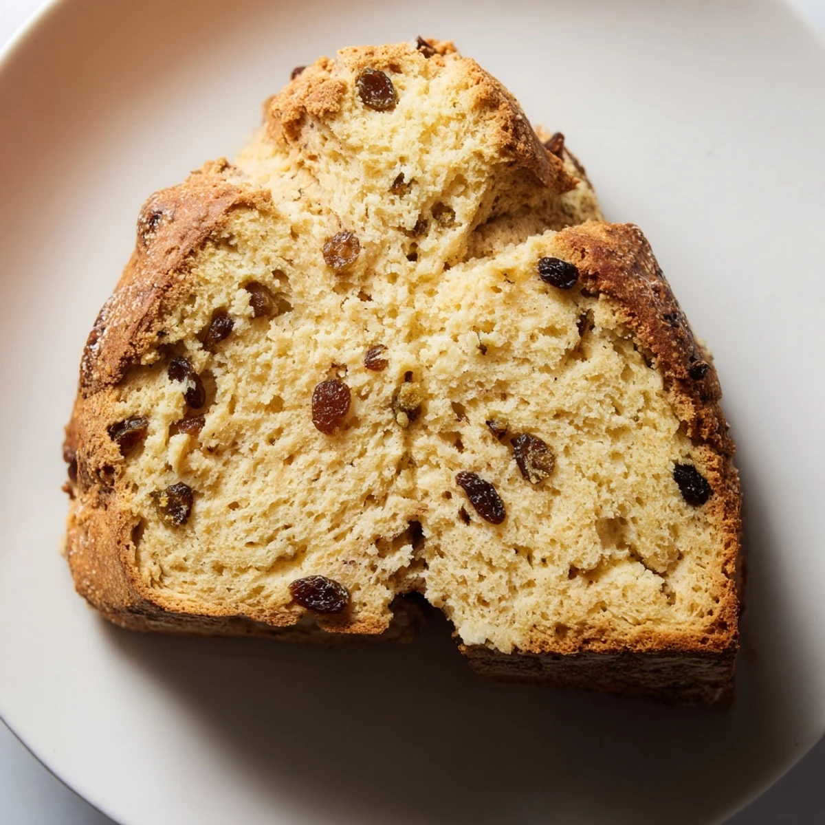 A freshly baked Irish Soda Bread with Raisins and Caraway on a wooden board, showcasing a golden crust and crumbly texture.