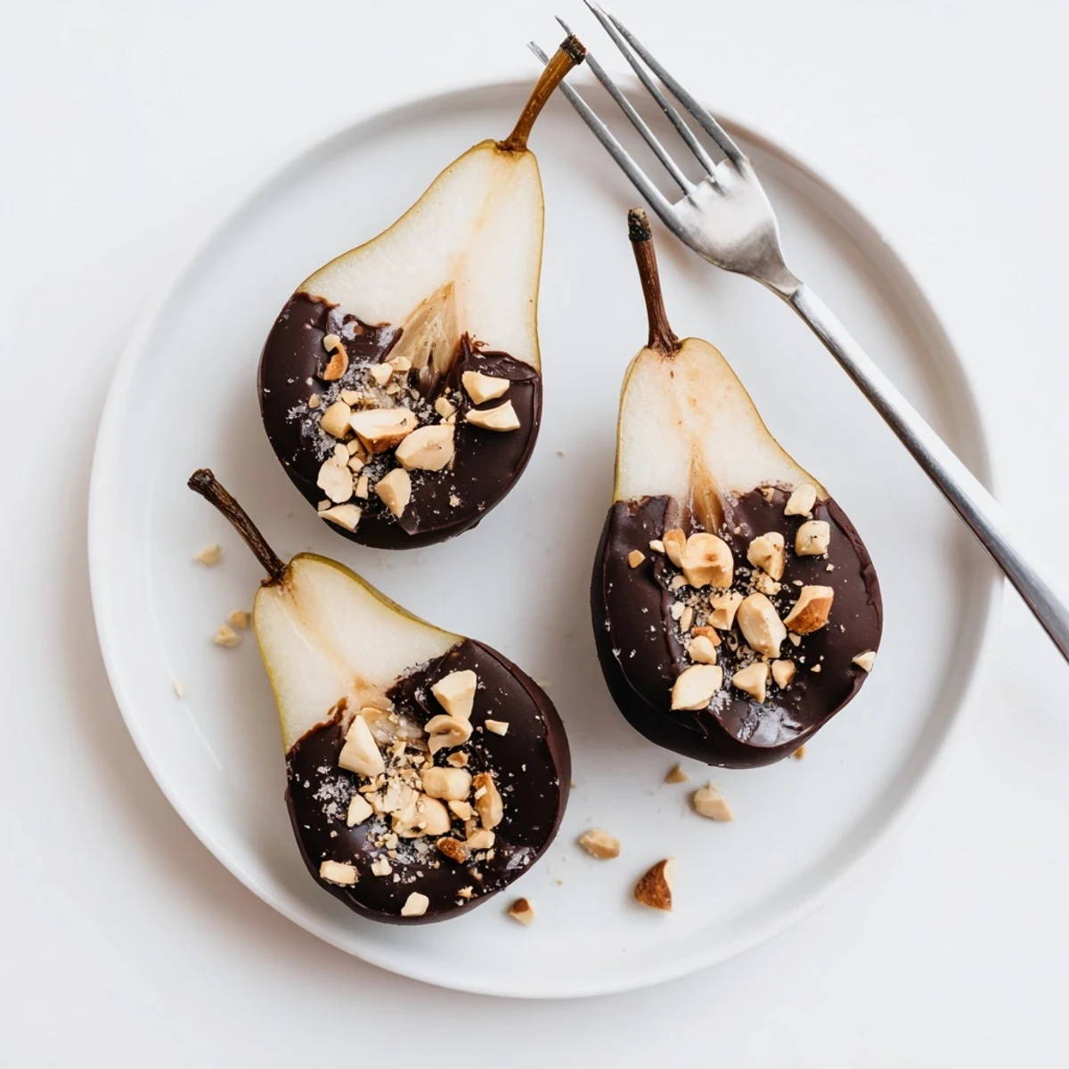 Stemmed Chocolate Covered Pears dipped in glossy dark chocolate, finished with a pinch of sea salt for a sweet-salty bite.