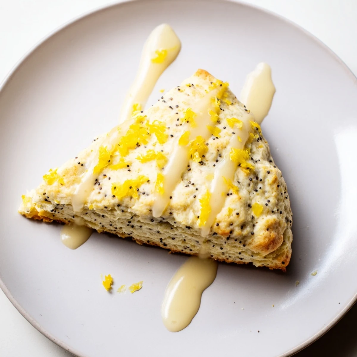 Golden-brown Lemon Poppy Seed Scones drizzled with white icing, perfect for an afternoon tea or breakfast spread.