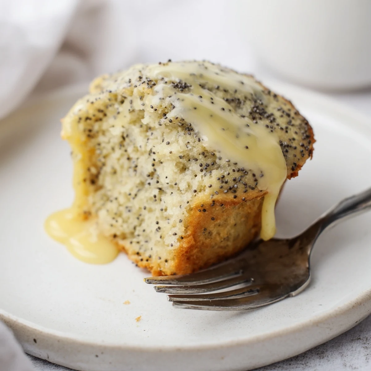 Freshly baked Lemon Poppy Seed Muffins with a drizzle of sweet lemon glaze on a cooling rack.