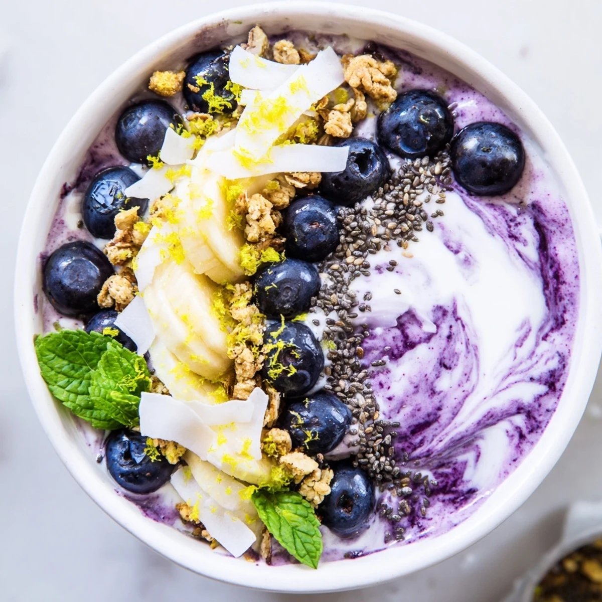 A vibrant Lemon Blueberry Smoothie Bowl with creamy purple base and crunchy toppings.