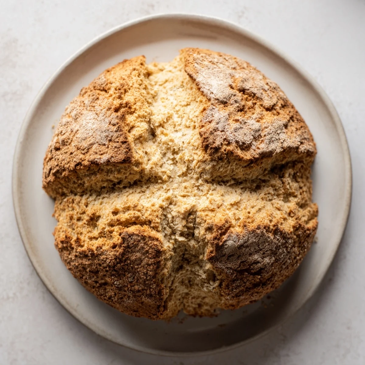 Slices of the Authentic 4-Ingredient Irish Soda Bread reveal a tender, soft crumb, served warm on a plate beside a pat of butter.  