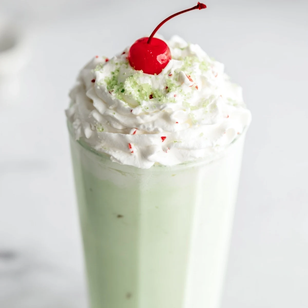 Blender preparing a frosty Homemade Copycat Shamrock Shake with vanilla ice cream, peppermint extract, and whole milk for a refreshing sweet treat.