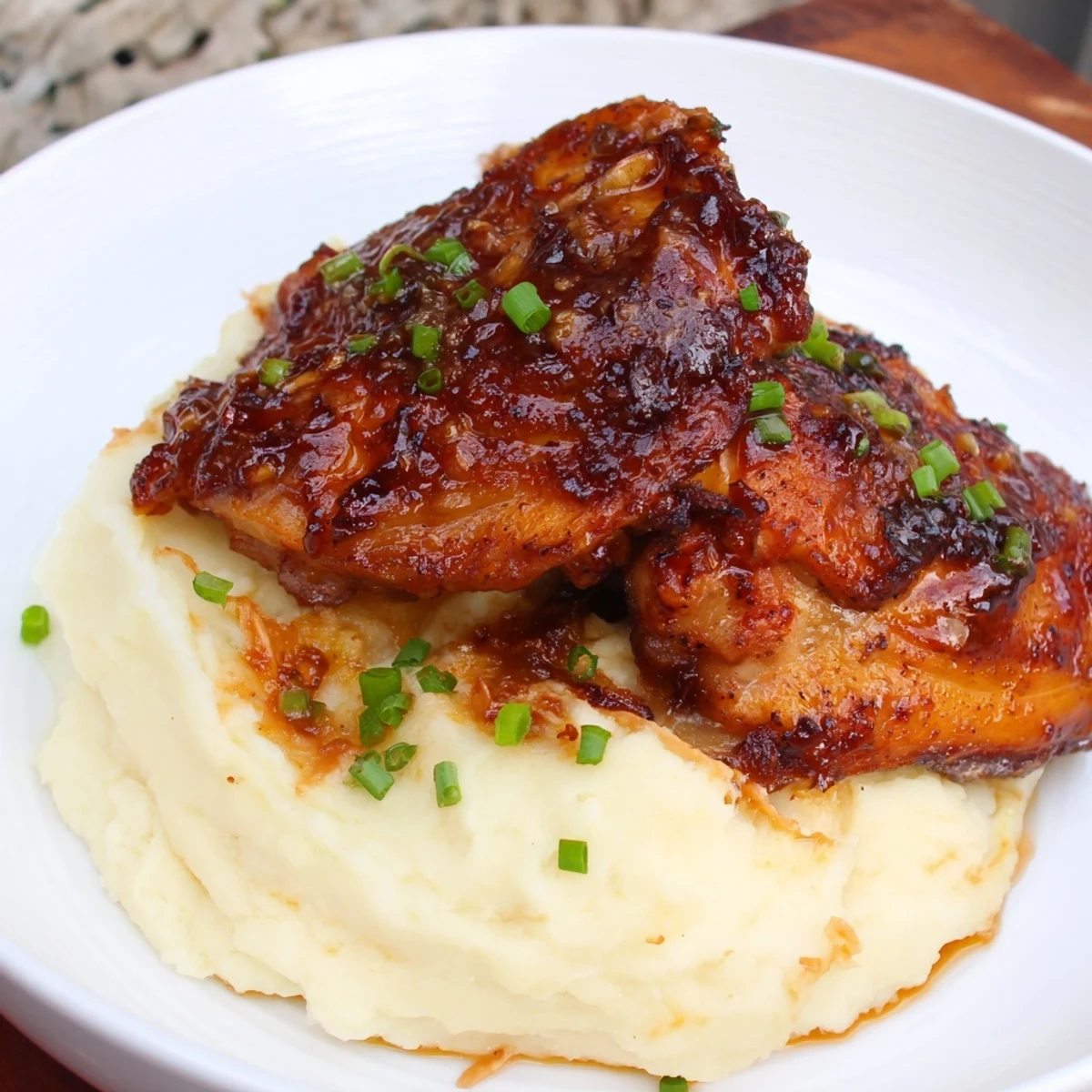 Perfectly caramelized chipotle honey chicken thighs paired with velvety smoked Gouda potatoes on a rustic dinner plate.