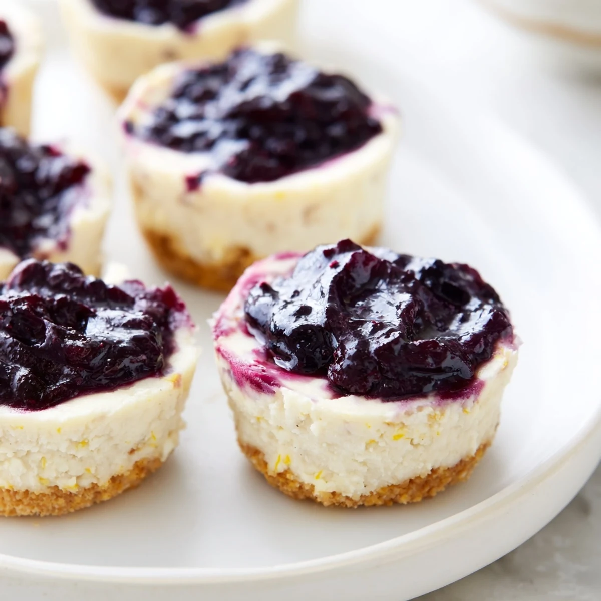 Stack of soft Blueberry Cheesecake Protein Bites beside a glass of milk for a wholesome snack.