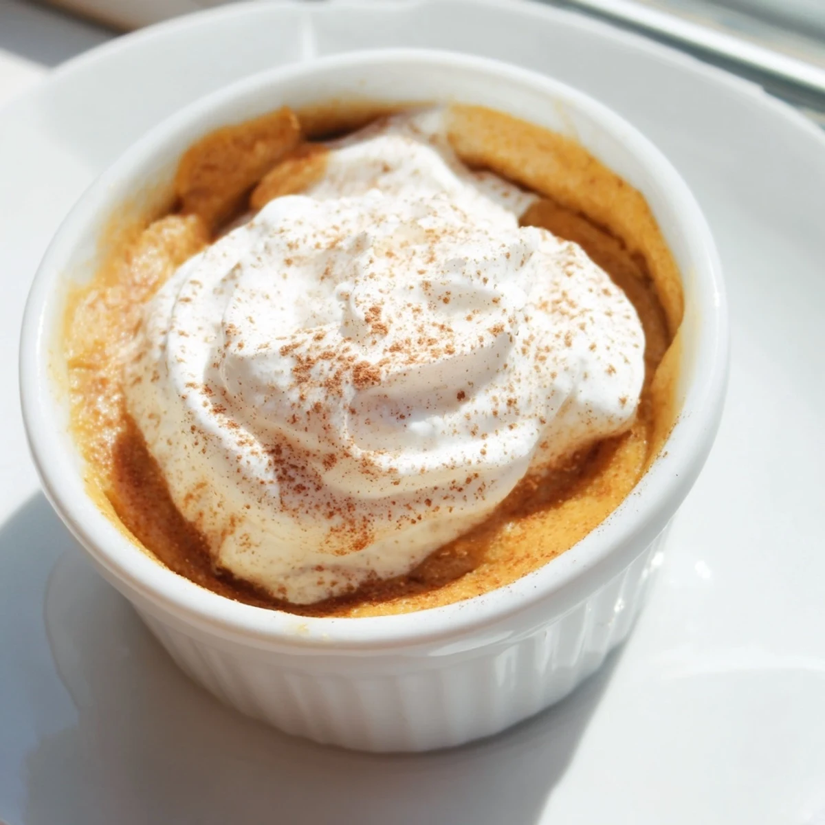 Individual ramekins of baked pumpkin spice pudding with a wobbly center, perfect for autumn dessert.
