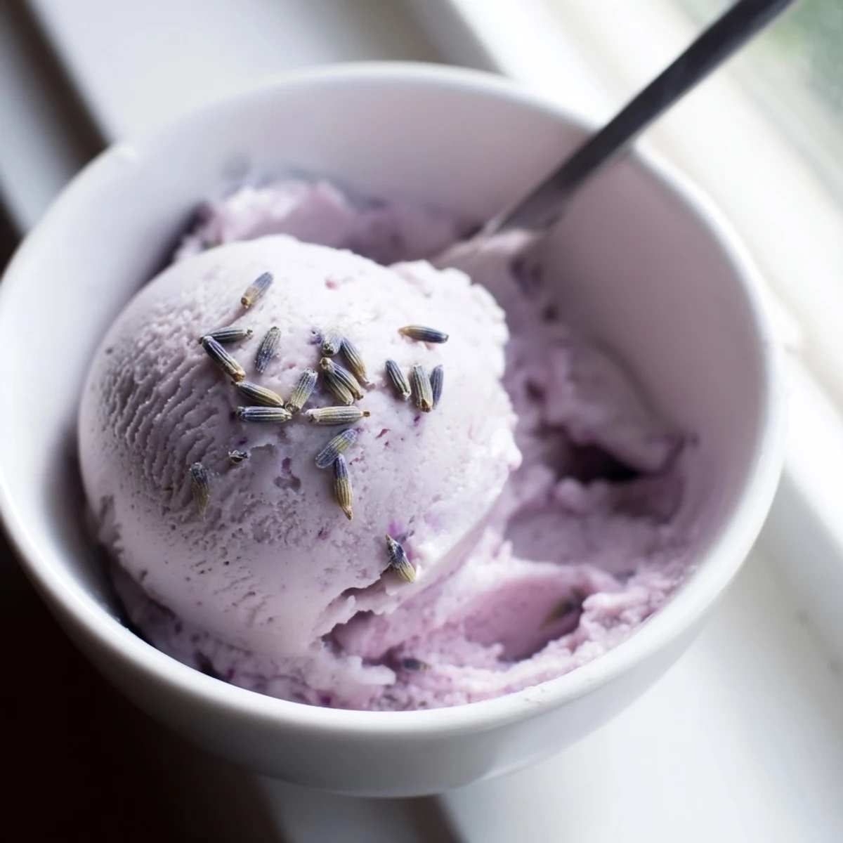 Lavender Ice Cream served in a vintage glass dish alongside a buttery shortbread cookie, evoking an elegant French-inspired treat.