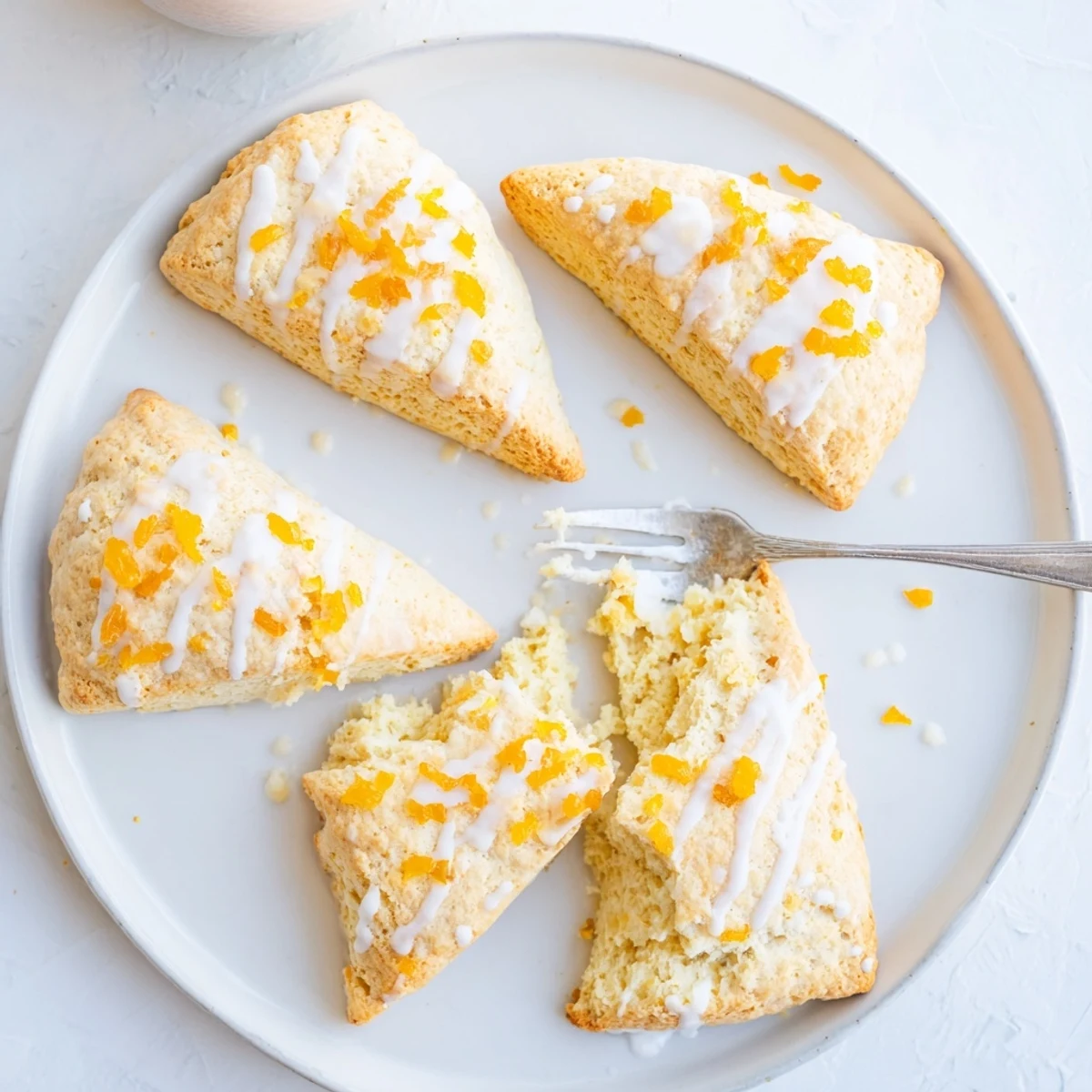 Warm Candied Ginger Orange Scones served on a rustic plate with clotted cream and orange zest garnish.