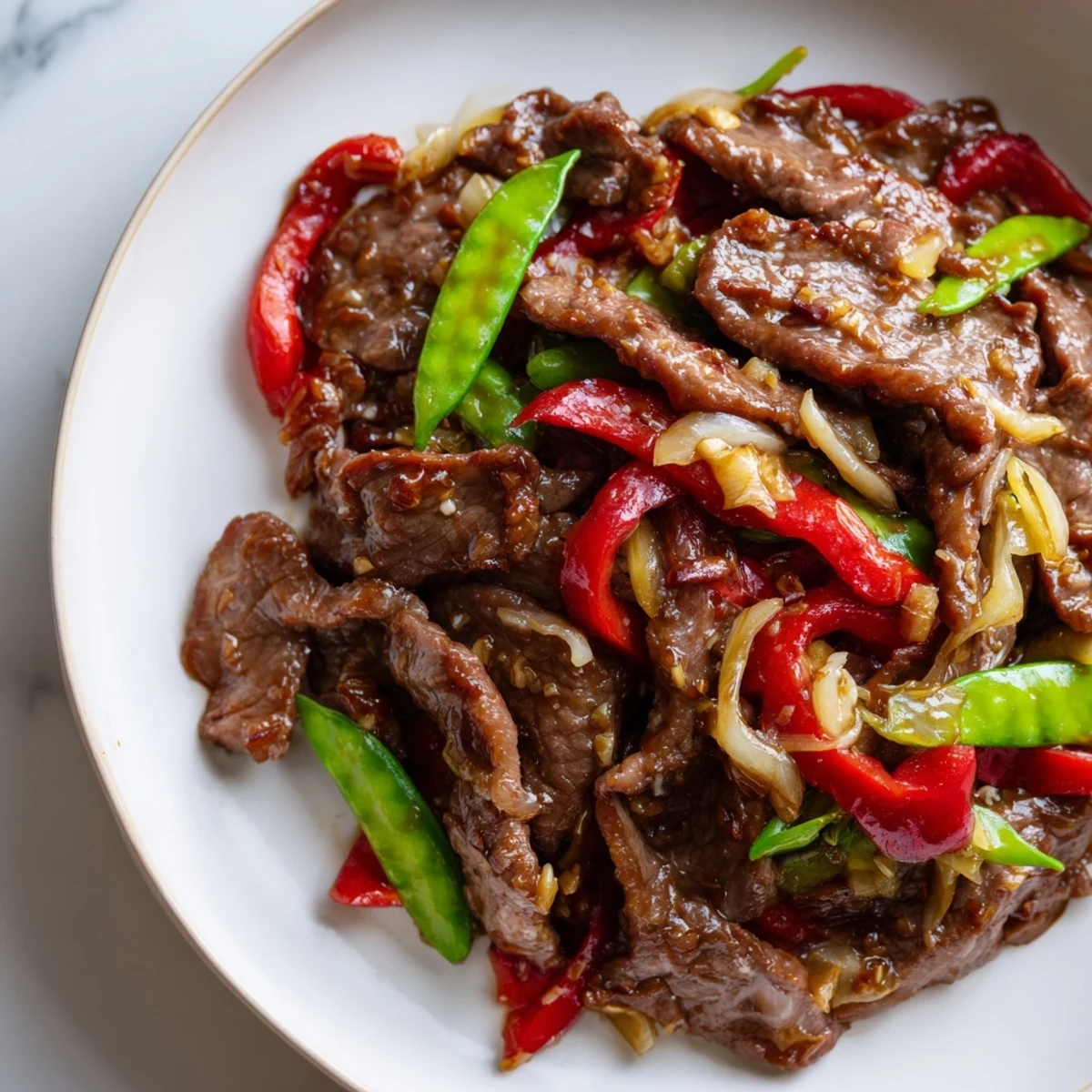 Glossy, tender Beef With Oyster Sauce stir-fry with crisp bell peppers and snow peas ready to serve over steamed rice.