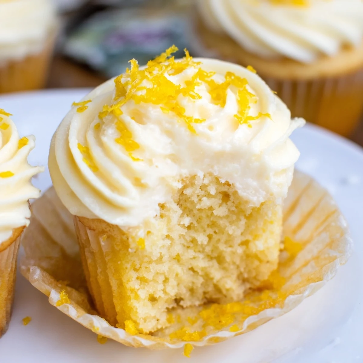 A plate of Limoncello cupcakes showcasing moist crumb and creamy Italian-inspired frosting beside lemon slices.