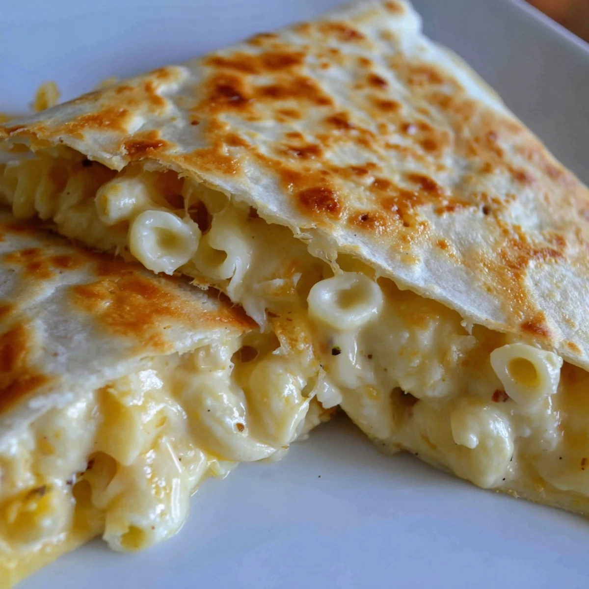 Golden crispy mac and cheese quesadilla cut into wedges on a white plate