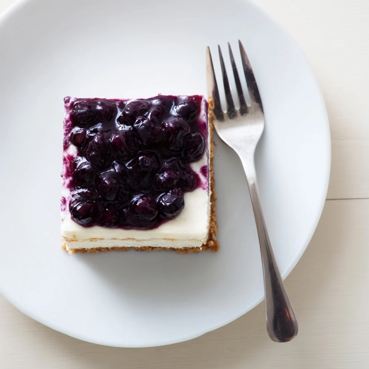 Rich blueberry cheesecake featuring graham cracker crust and glossy fruit topping ready to serve