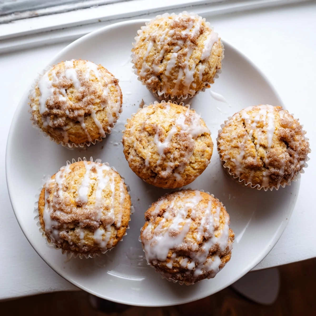 Golden cinnamon roll protein muffins topped with sweet white icing and dusted with cinnamon powder