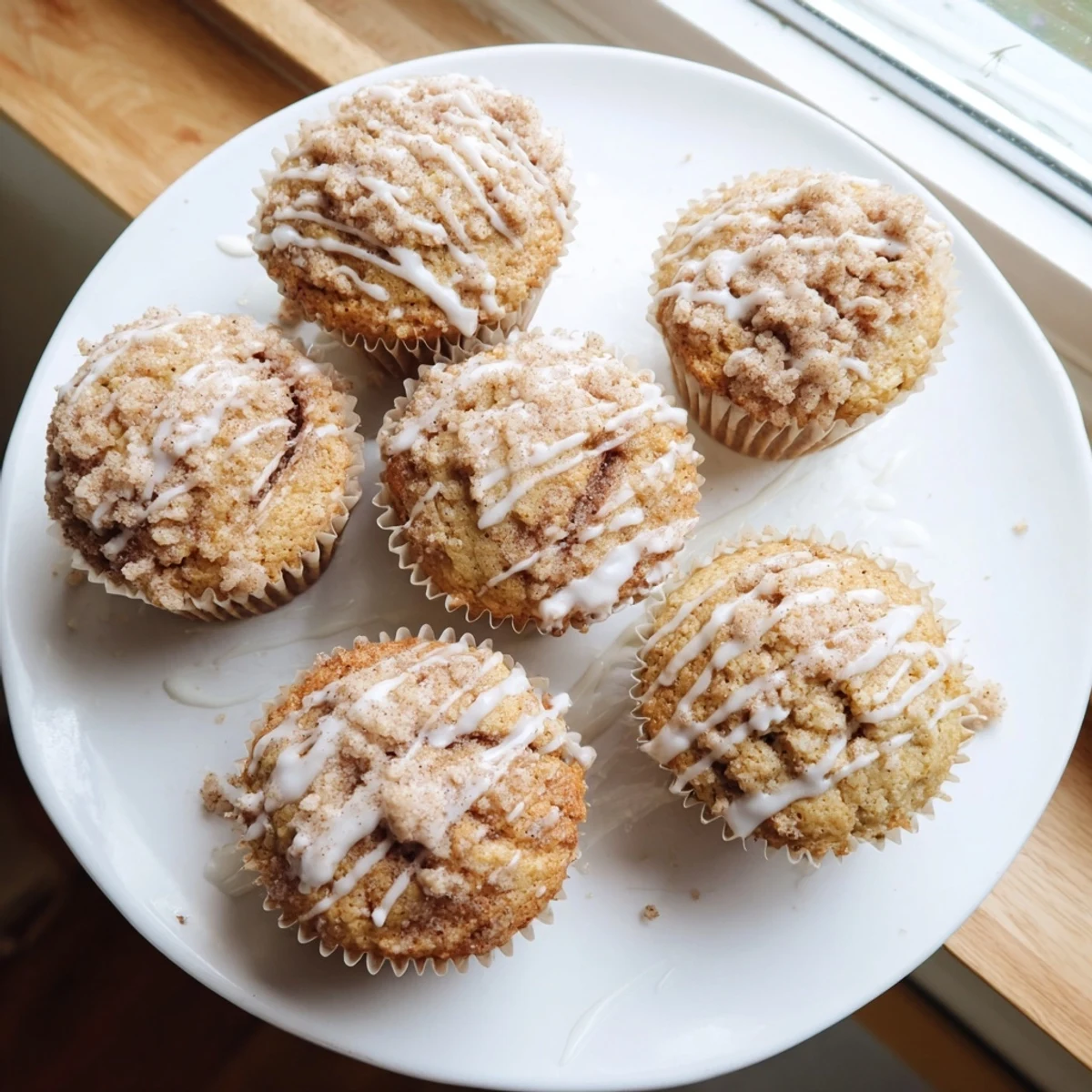 Freshly baked cinnamon roll protein muffins with moist crumb texture and sweet glaze drizzle on top