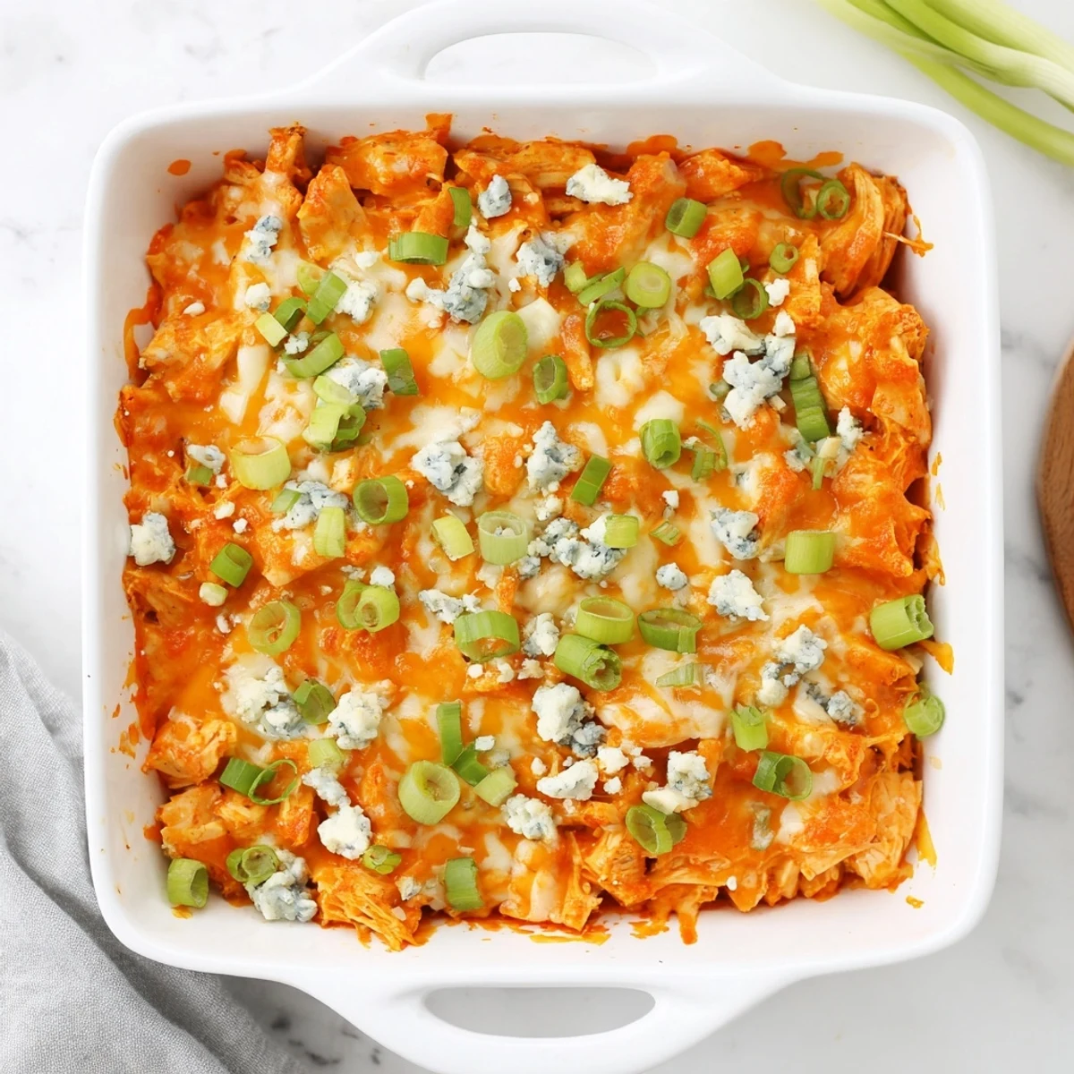 Hearty buffalo chicken cheese bake casserole served with celery sticks and tortilla chips for game day entertaining