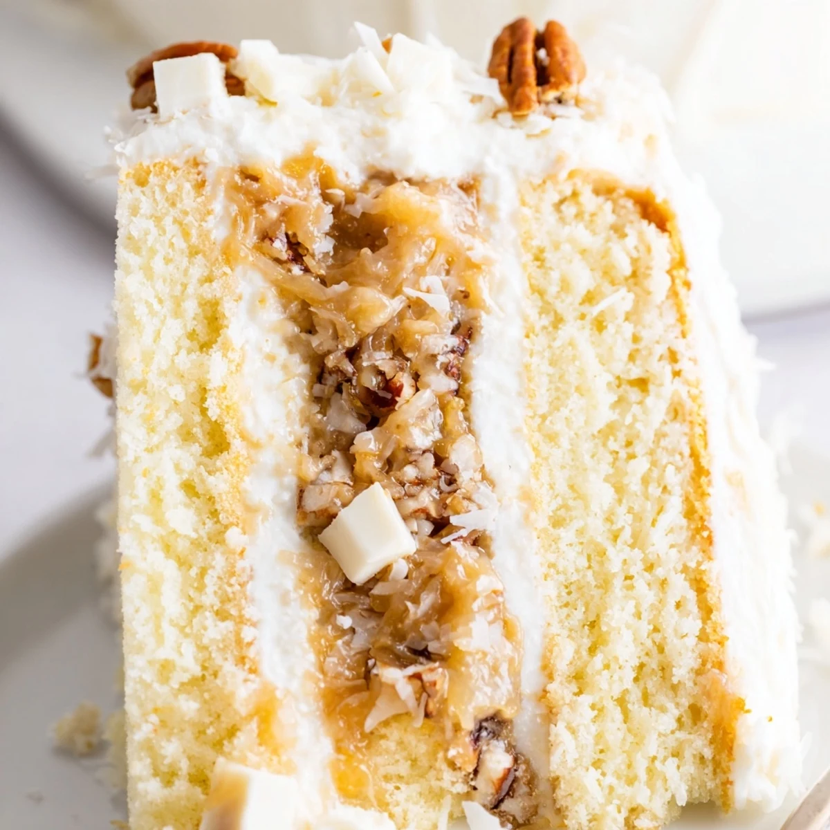 White German Chocolate Cake with three fluffy layers and coconut-pecan filling between white chocolate cake slices