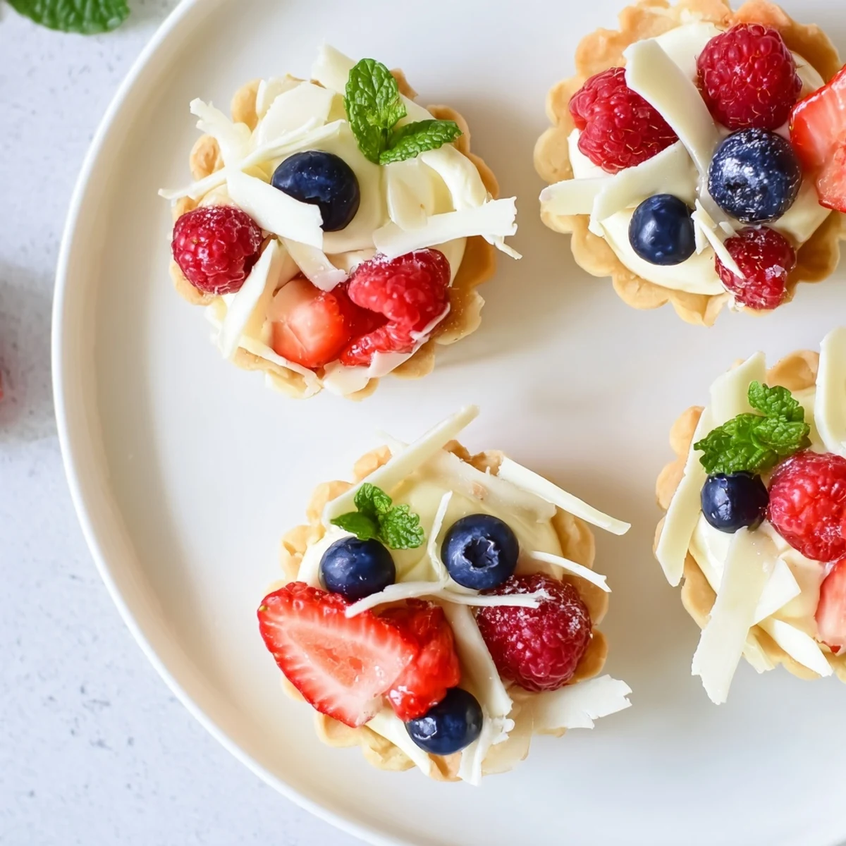 Golden pastry tartlets filled with creamy white chocolate mousse topped with fresh mixed berries