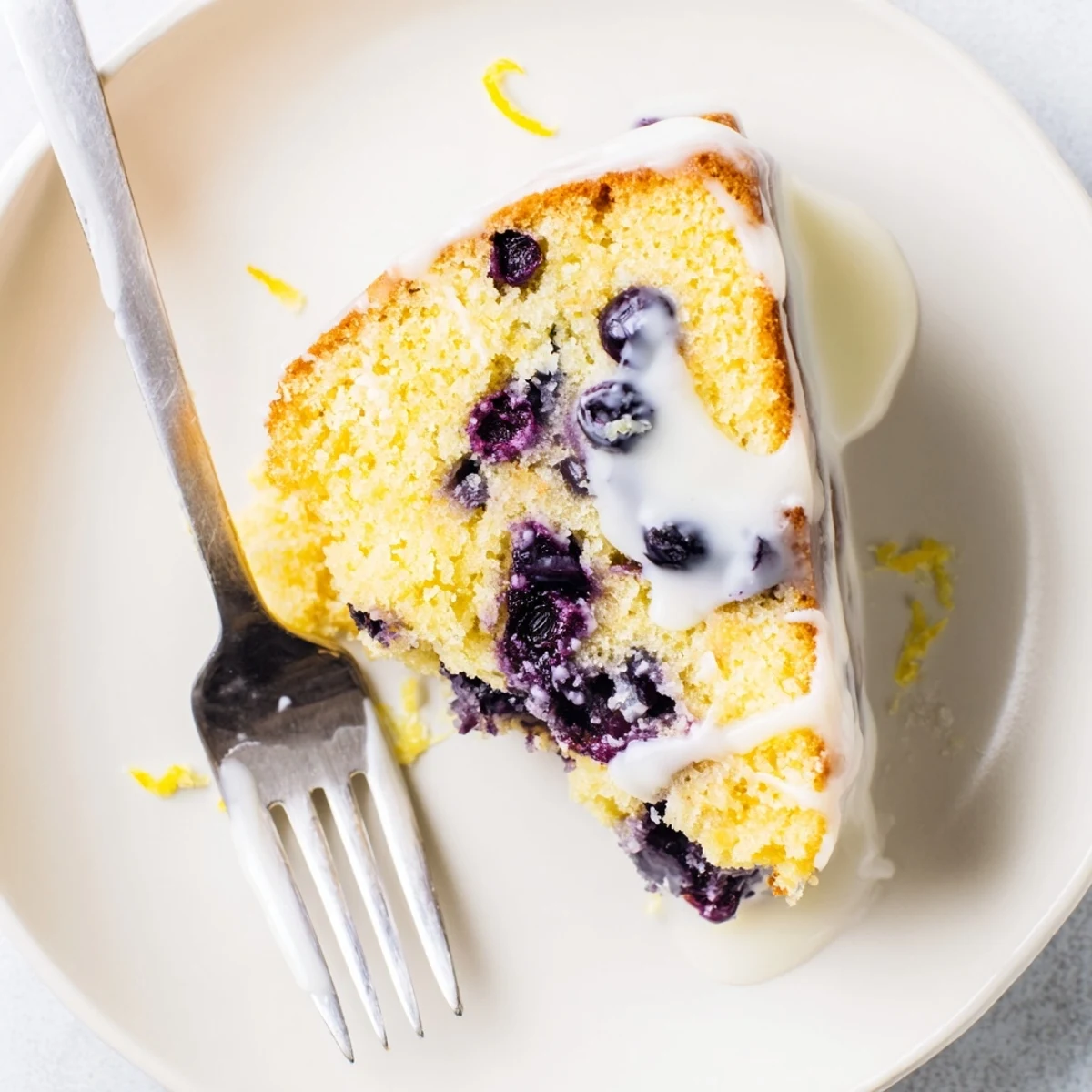 Golden lemon blueberry cake drizzled with tangy glaze and fresh blueberries on top