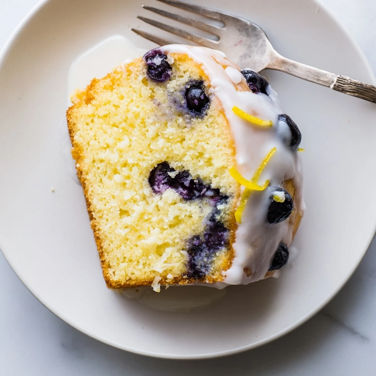 Moist lemon blueberry cake slice revealing vibrant blueberry bursts and tender yellow crumb