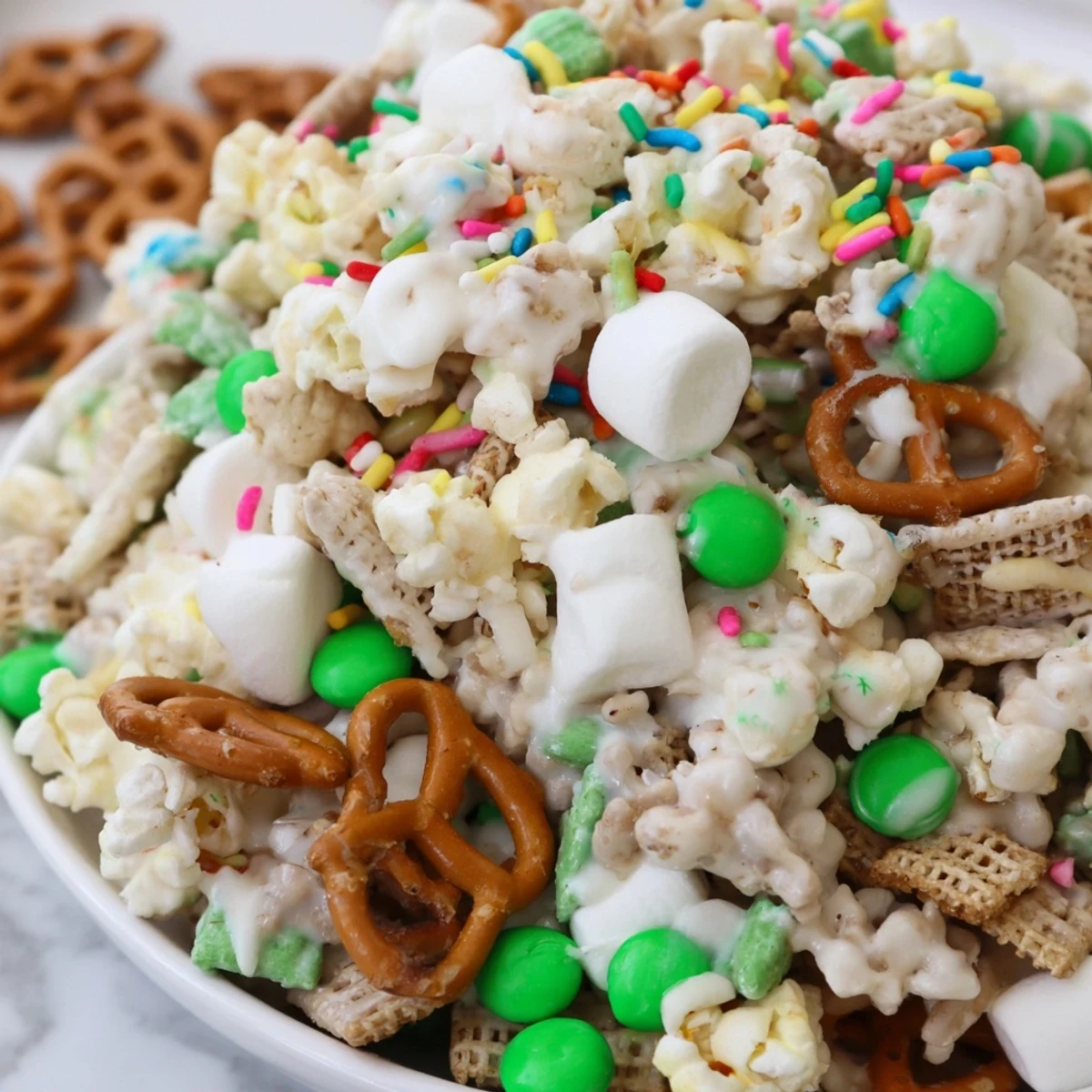 Festive Leprechaun Bait snack mix with colorful green candies, pretzels, and white chocolate drizzle