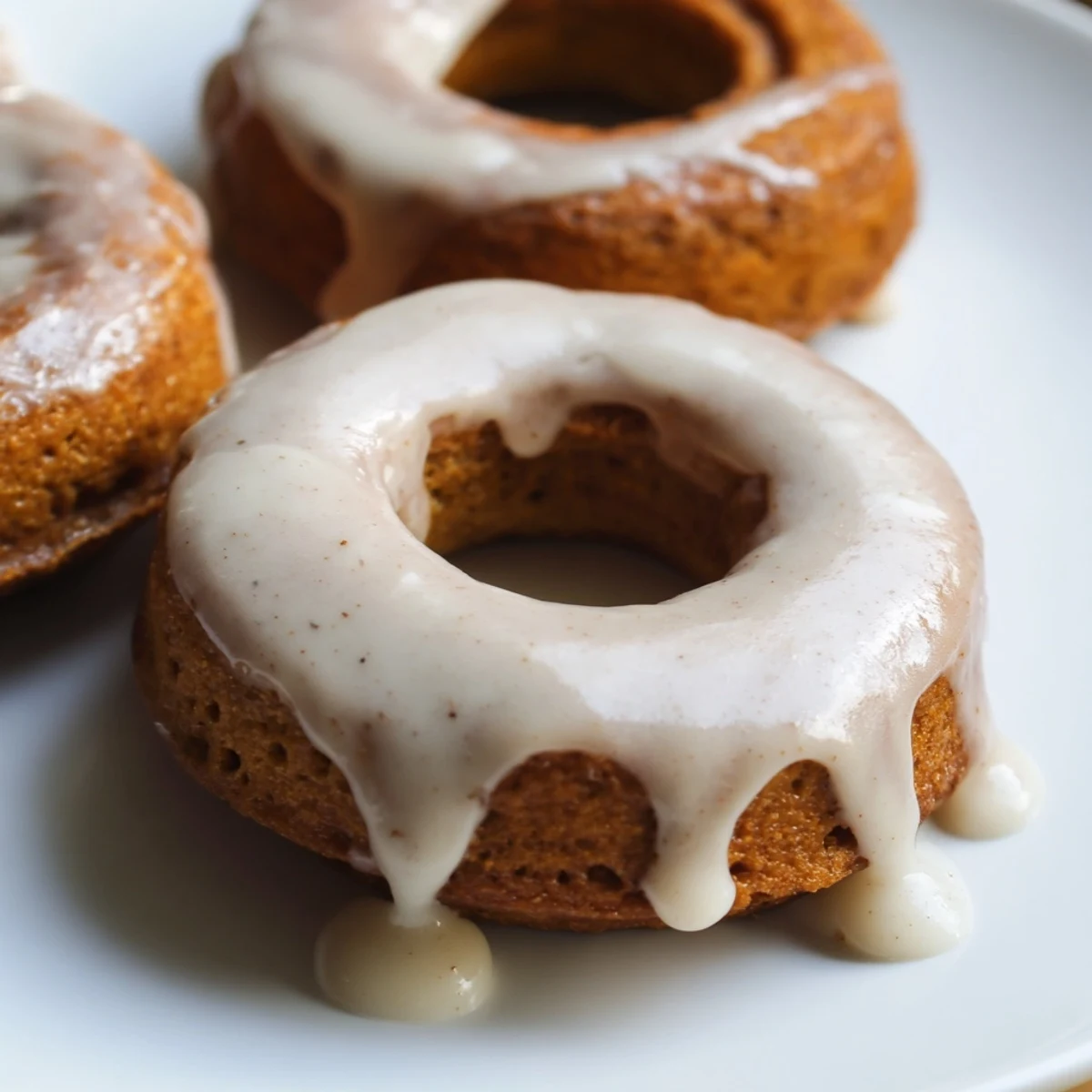 Chewy baked maple pumpkin mochi donuts topped with glossy maple glaze on wire rack