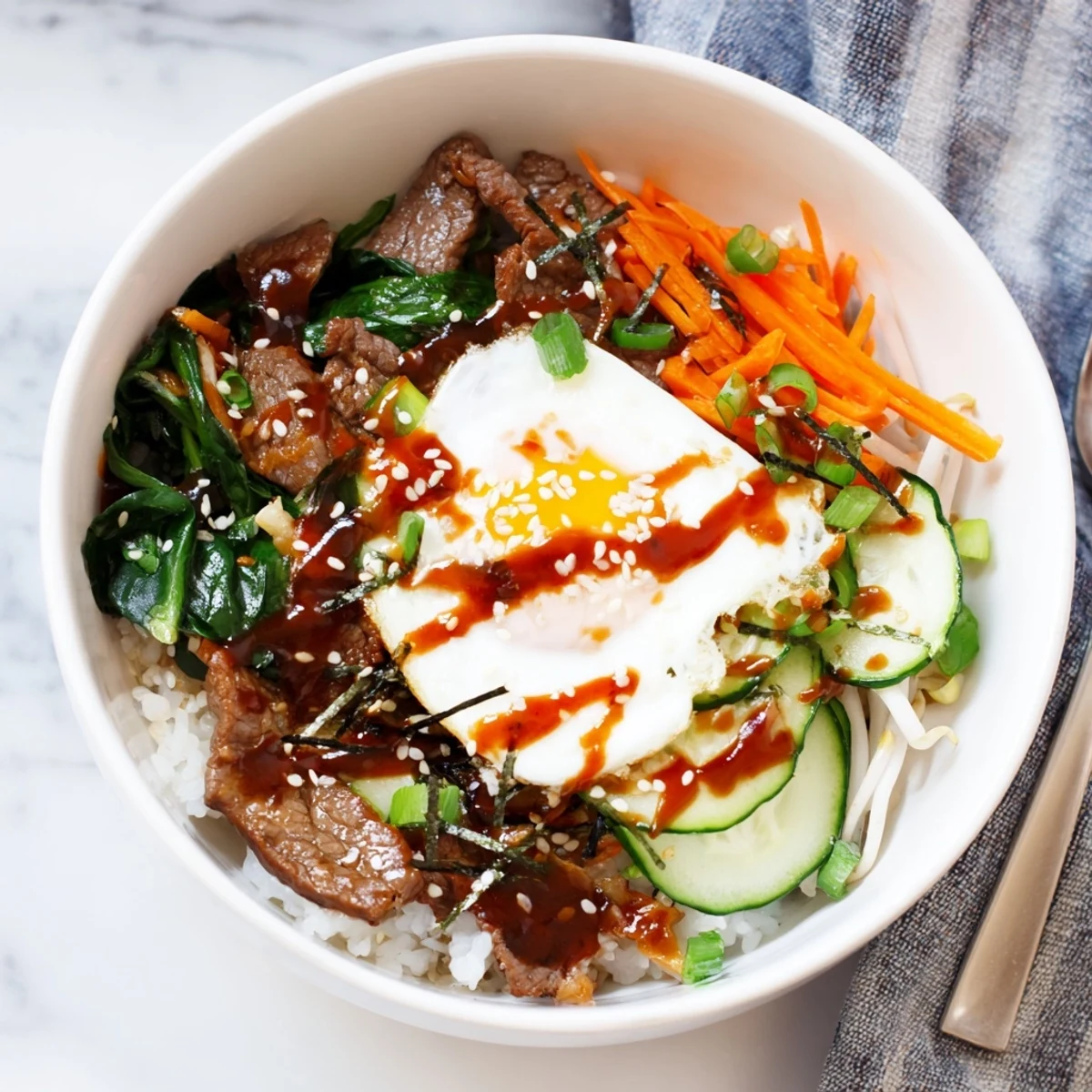 Savory Korean breakfast bowl topped with sunny-side egg, fresh vegetables, and spicy gochujang drizzle
