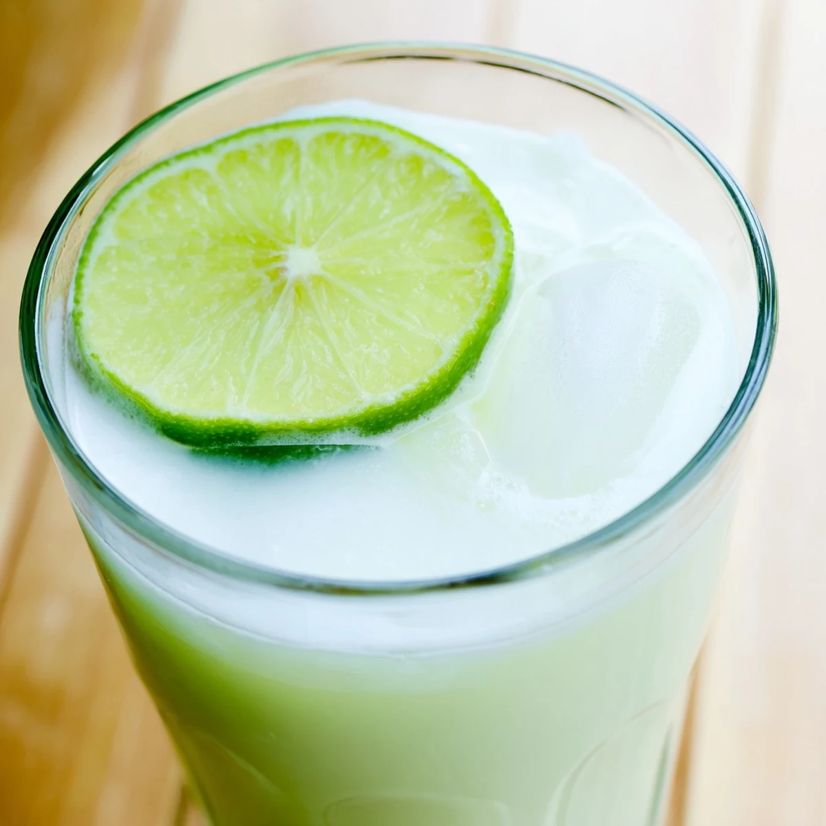 Frosted glass of creamy Brazilian lemonade garnished with fresh lime slices on ice