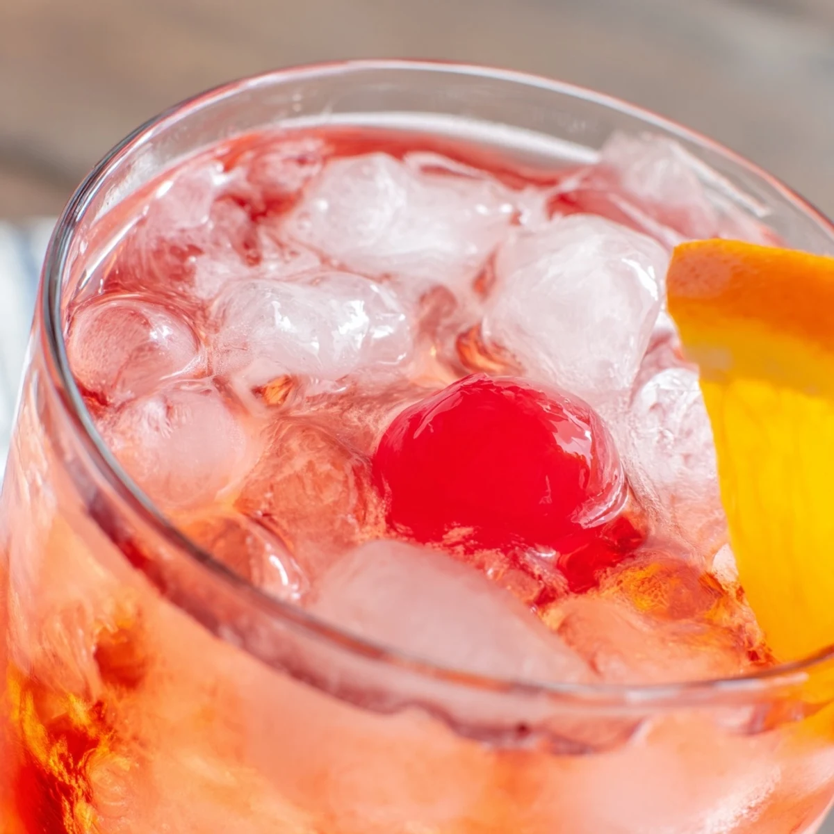 Sparkling Easy Shirley Temple drink with grenadine swirl, ice cubes, and bright red cherry garnish in a tall glass