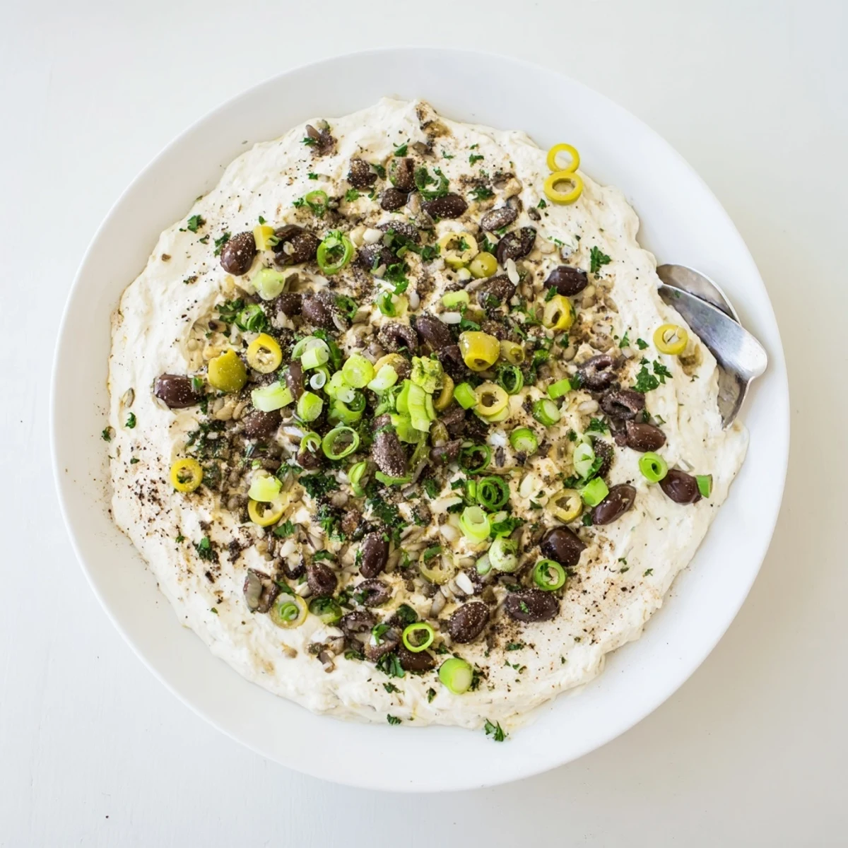 Cream cheese olive dip topped with colorful chopped green and black olives and fresh green onions