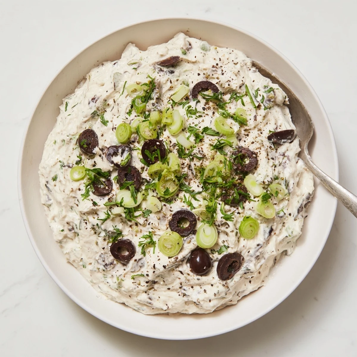 Cream cheese olive dip plated with crispy crackers and fresh parsley garnish for party entertaining