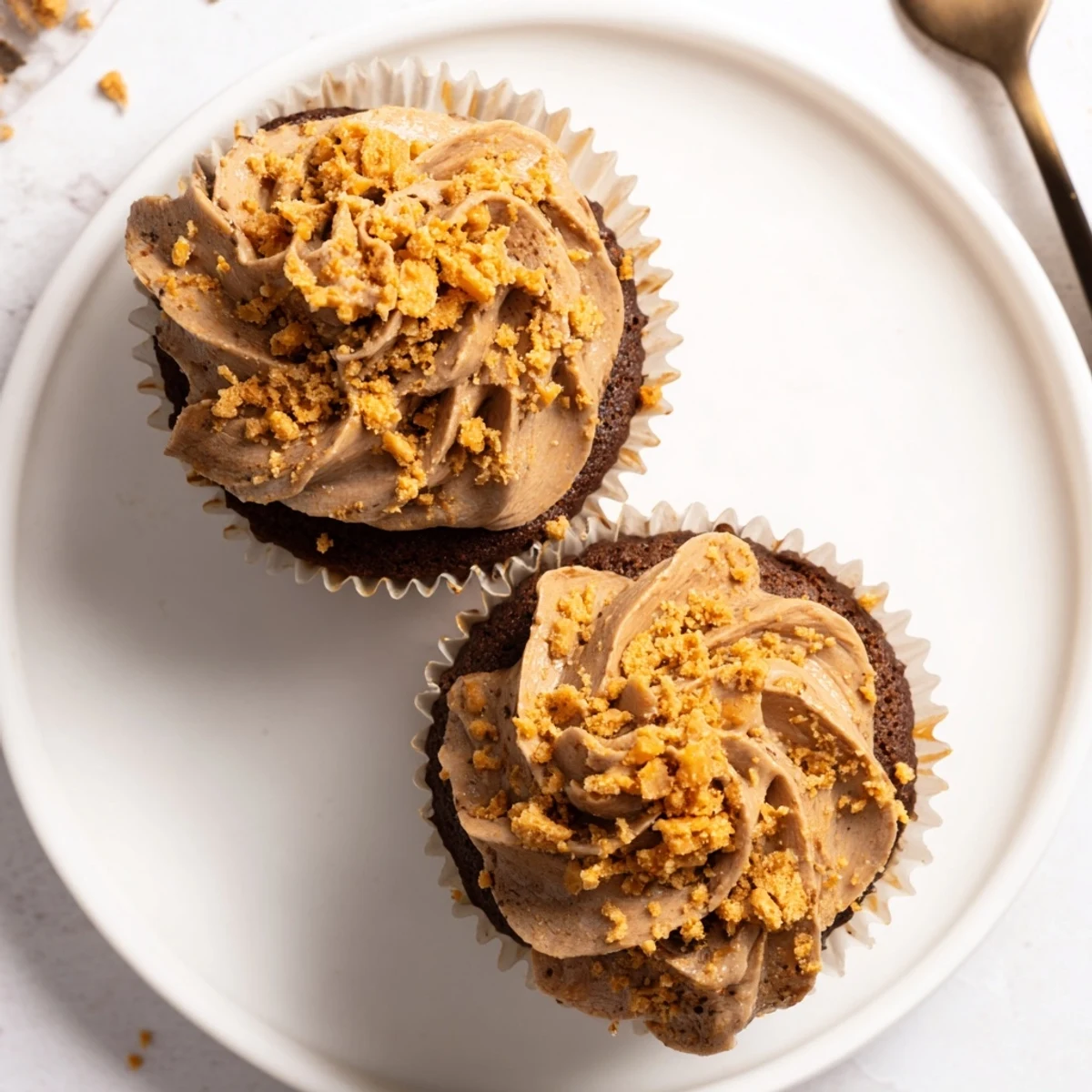 Decadent Butterfinger cupcakes topped with fluffy peanut butter frosting and scattered with crunchy candy bar pieces