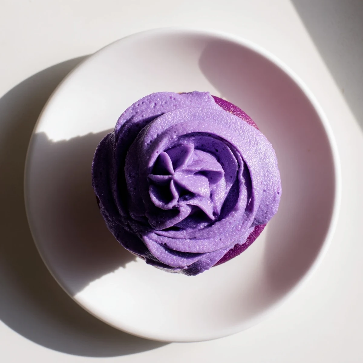 Fluffy purple grape soda cupcakes topped with swirls of tangy grape buttercream frosting on a white plate