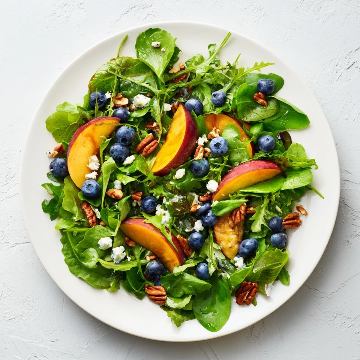 Fresh blueberry peach salad with crumbled feta and mixed greens drizzled with balsamic dressing