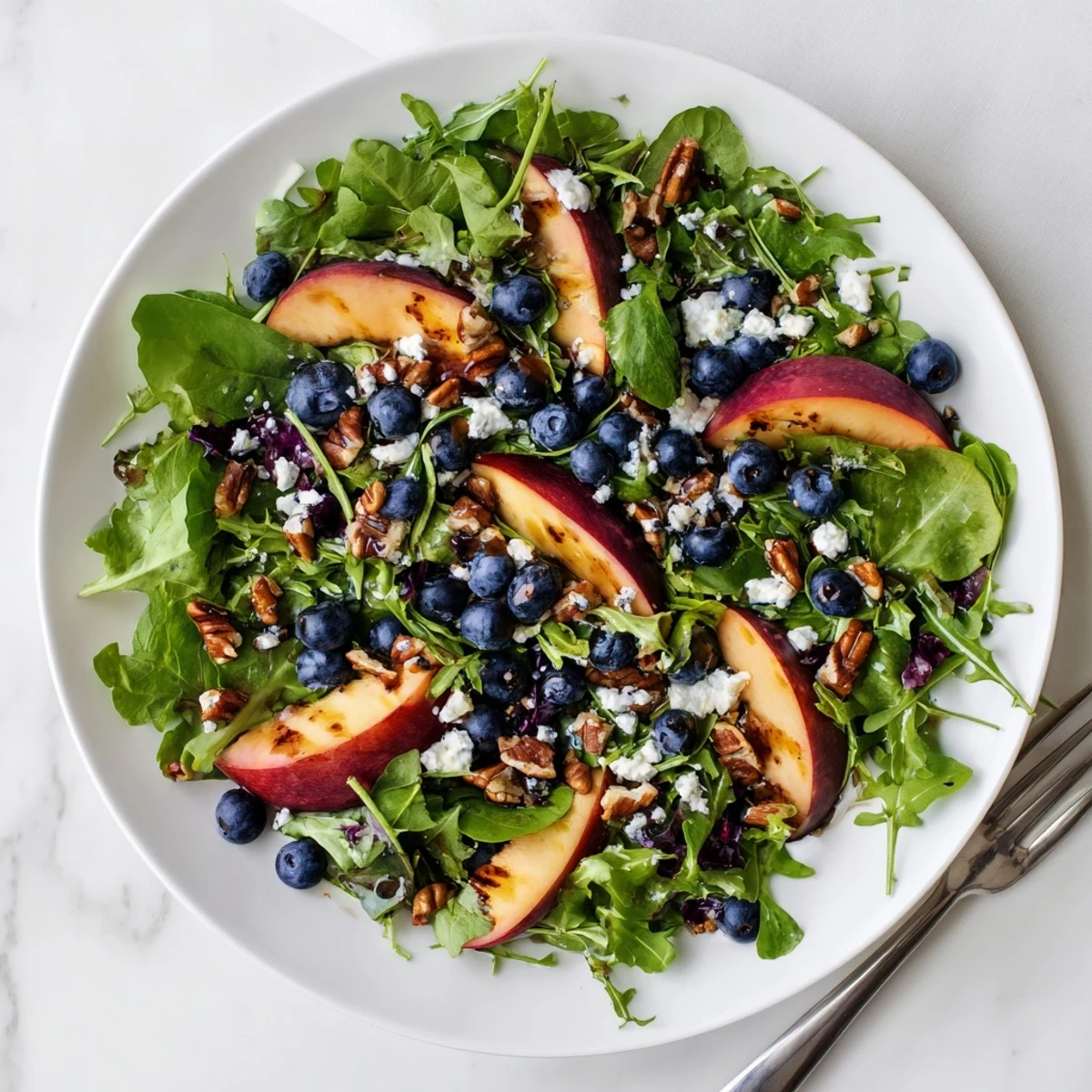 Vibrant summer salad featuring sweet peaches, juicy blueberries, and creamy feta over crisp arugula