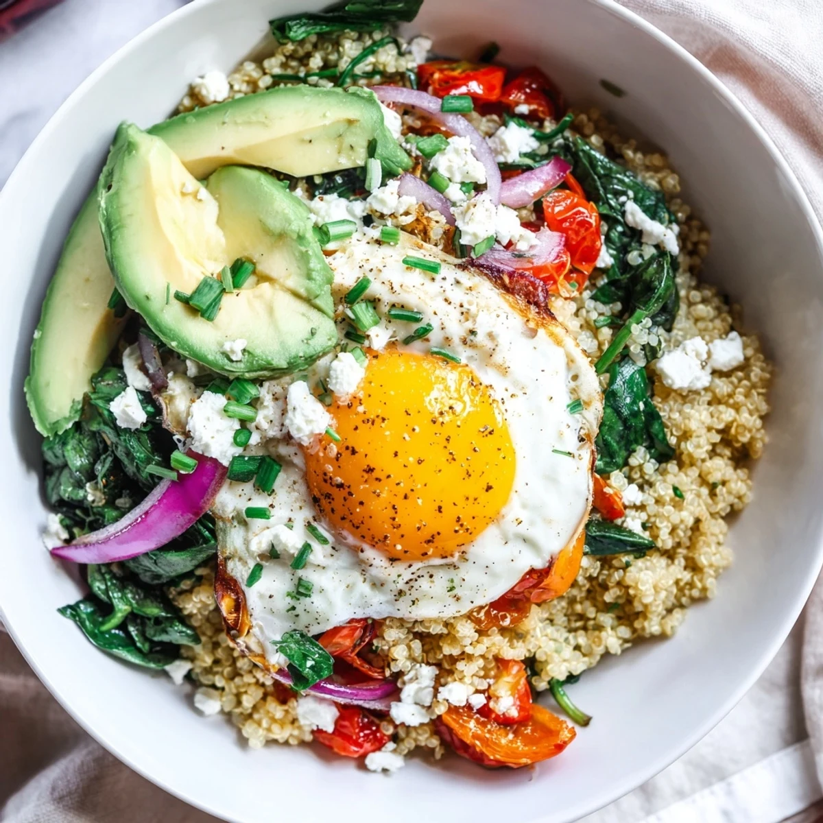 Protein-rich savory quinoa breakfast bowl garnished with fresh herbs, avocado, and runny fried egg