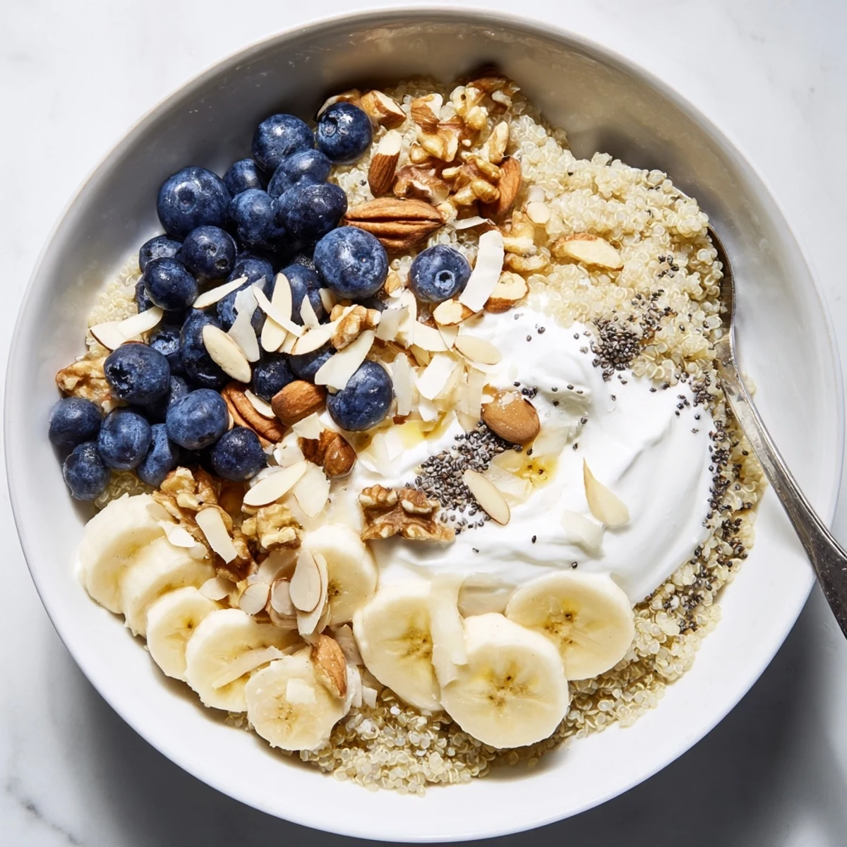 Warm blueberry quinoa breakfast bowl drizzled with maple syrup and fresh blueberry garnish