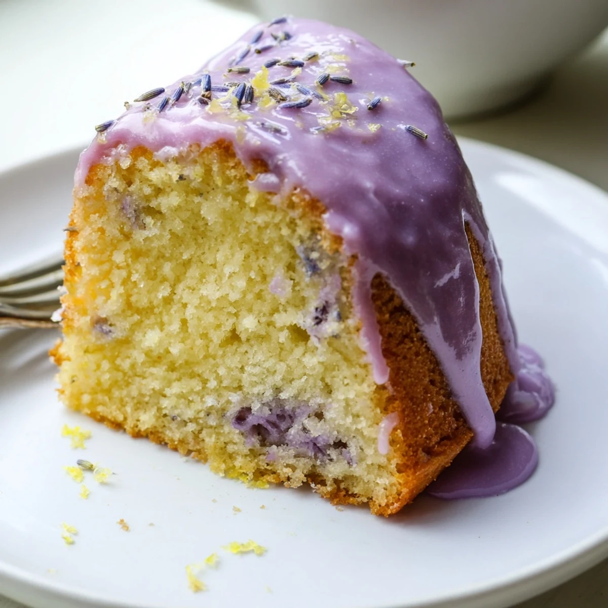 Soft lavender cake garnished with purple buds on a white plate