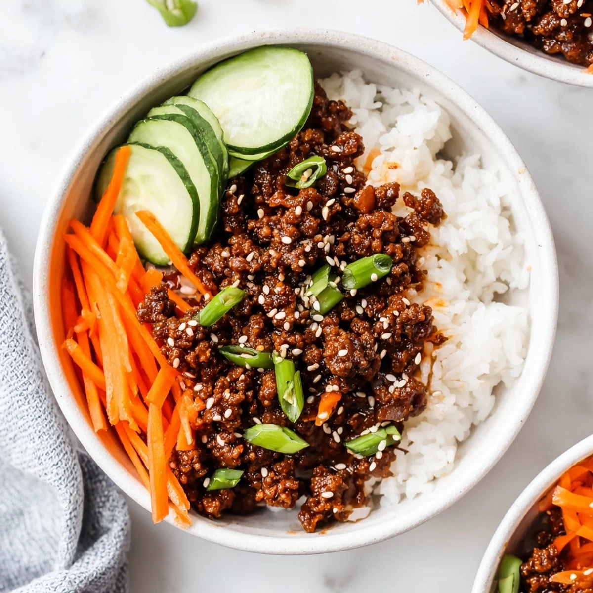 Korean beef bowls with caramelized ground beef fresh cucumber carrots and steamed jasmine rice