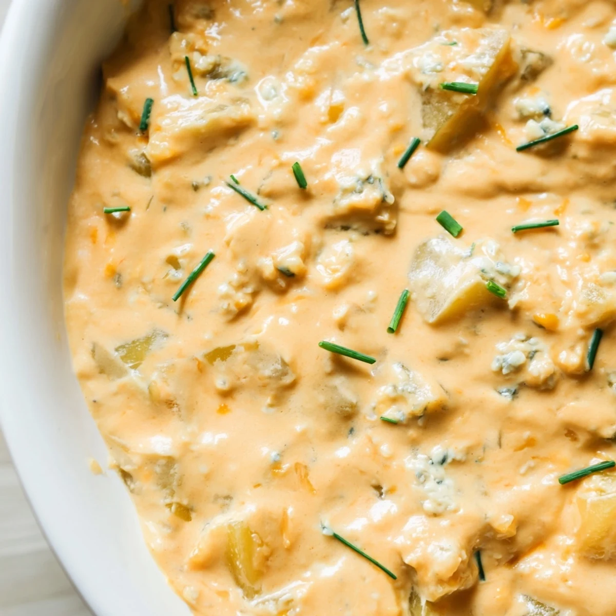 Tangy buffalo pickle dip topped with chopped chives and pickle slices served in a rustic ceramic bowl