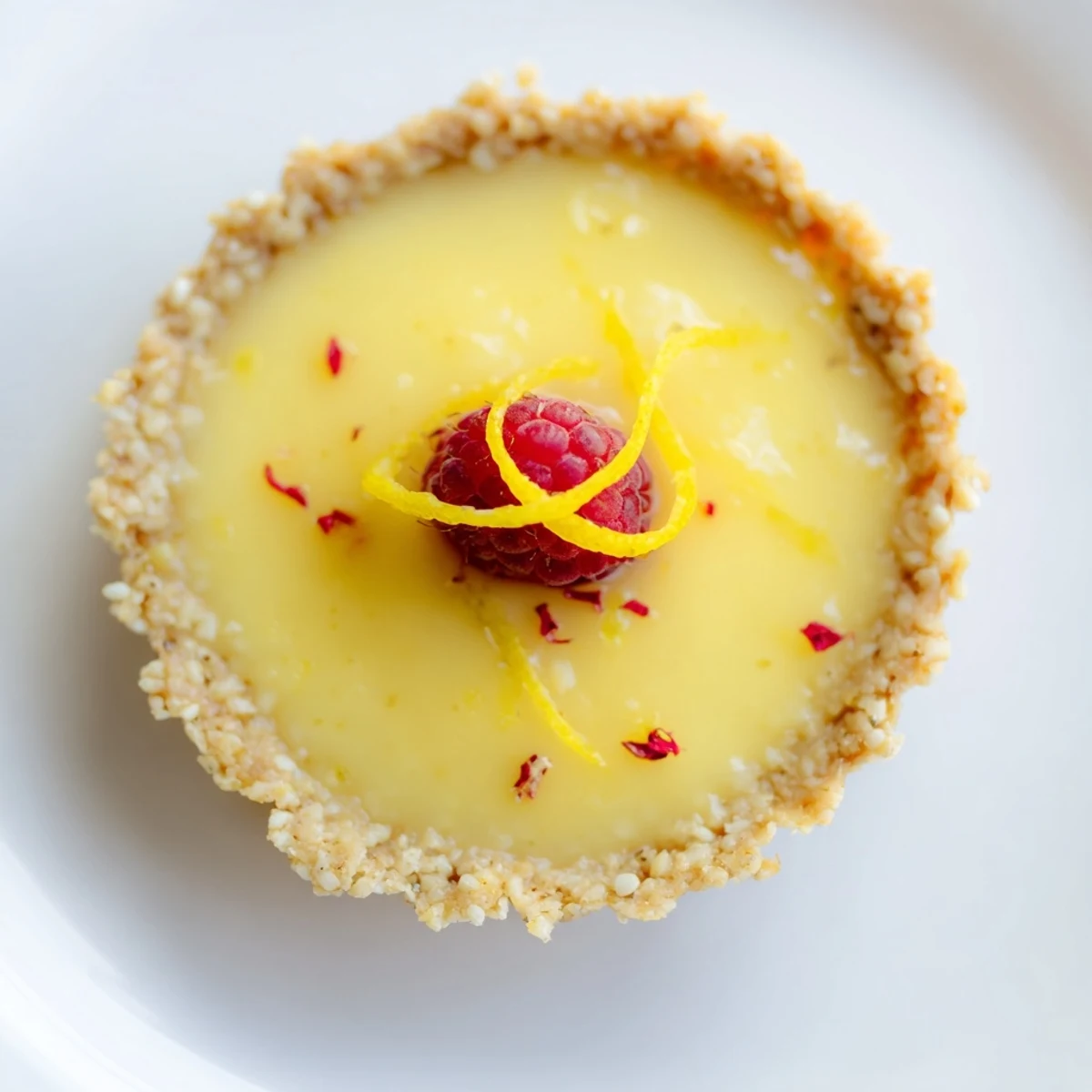 Golden mini vegan lemon tarts topped with fresh berries on a rustic white plate