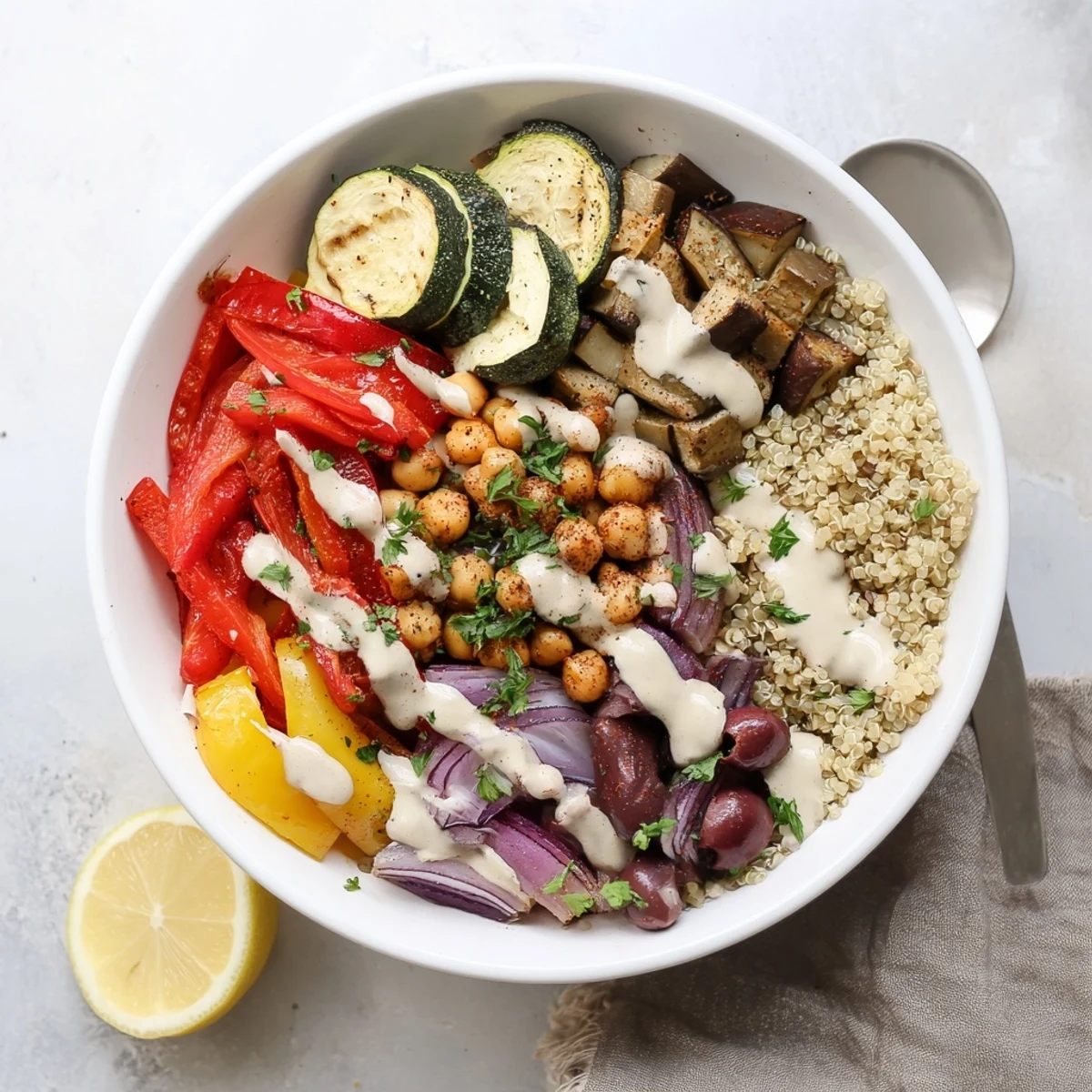 Golden roasted zucchini, eggplant, and chickpeas in a vegan Mediterranean roasted vegetables bowl drizzled with creamy tahini dressing