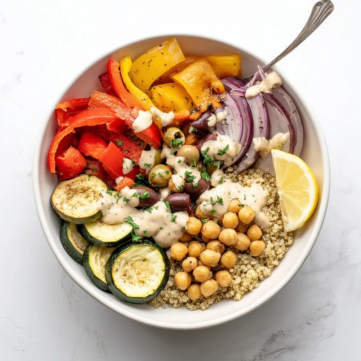 Warm vegan Mediterranean roasted vegetables bowl served over quinoa with charred bell peppers and fresh parsley garnish