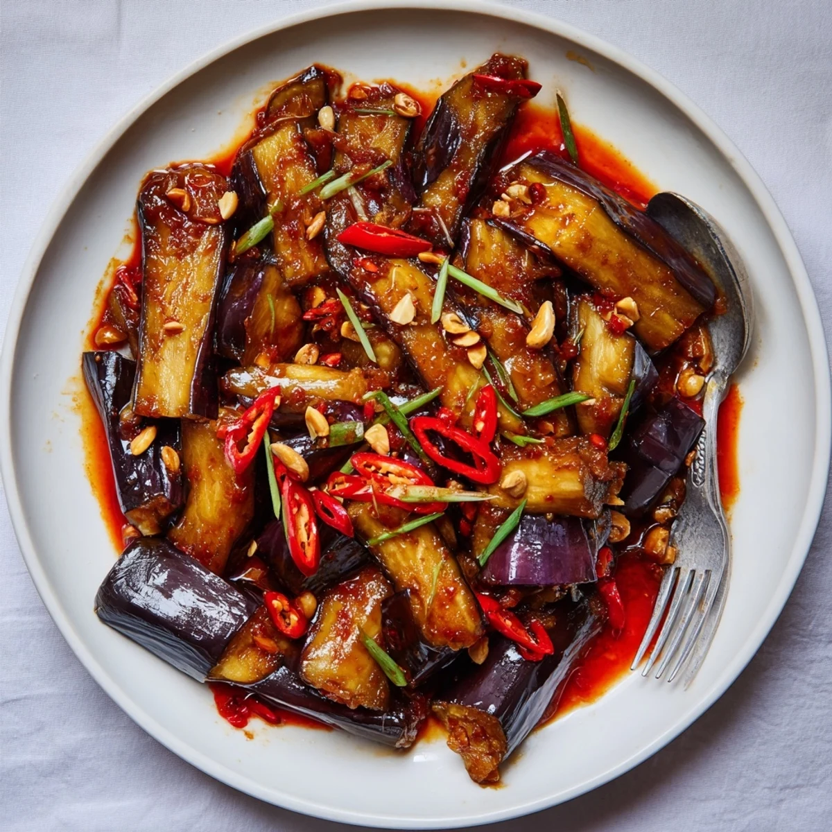 Warm Sichuan Style Braised Aubergines with fragrant garlic, ginger, and scallion garnish.